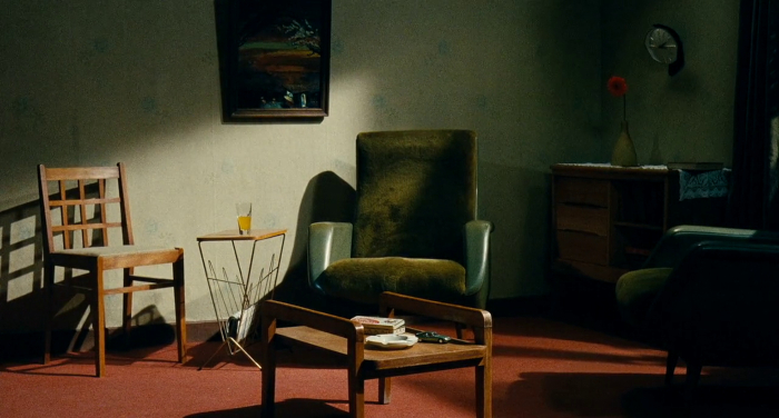 Imagem do filme O Porto: uma sala com duas poltronas e uma cadeira, e uma mesa no centro